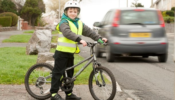 Young boy on his bicycle near road traffic