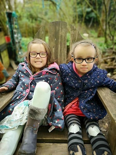 Matilda and Olivia sitting on a bench outdoors