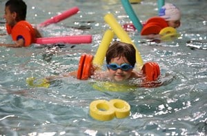 Children using pool floats while swimming.