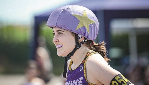 A deaf young woman wearing a roller derby helmet.
