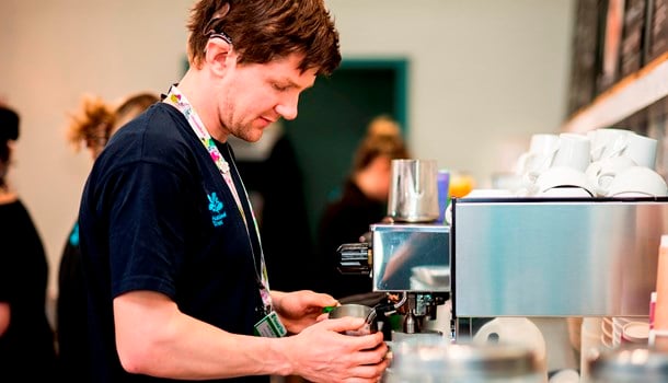 A deaf young man wearing cochlear implants working as a barista in a cafe.