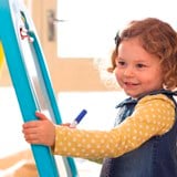 Young girl drawing on a whiteboard easel
