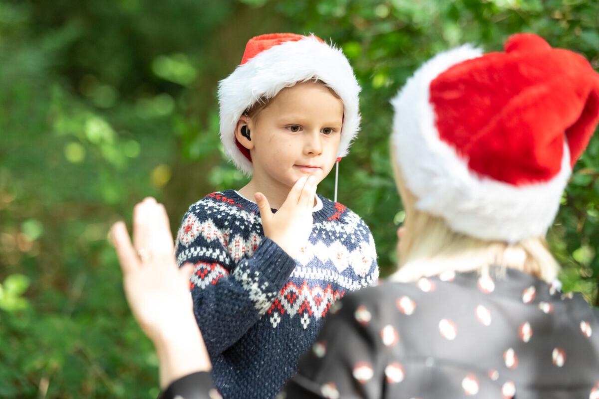 Rhys is wearing a Christmas and Santa hat and signs "thank you" to his mum in front of him.