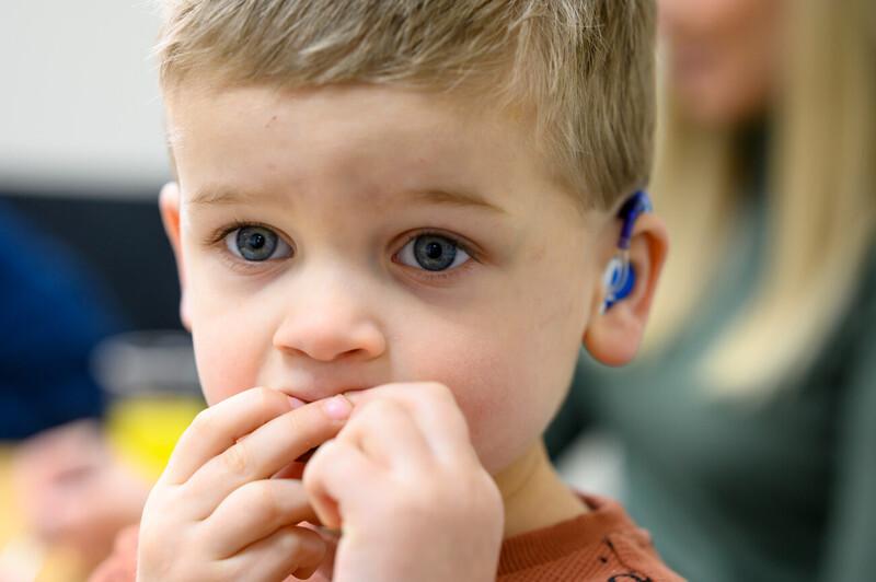Close up of the face of a young child who is wearing a hearing device