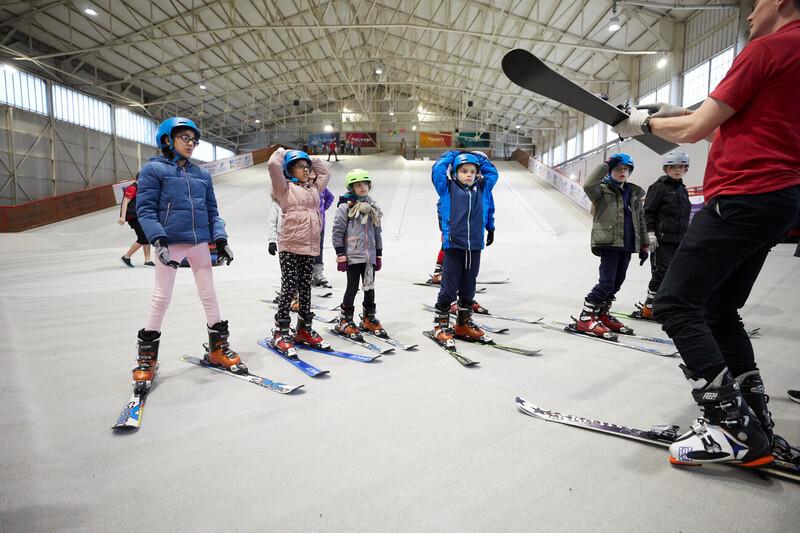 A group of children listening to a skiing instructor on a ski slope