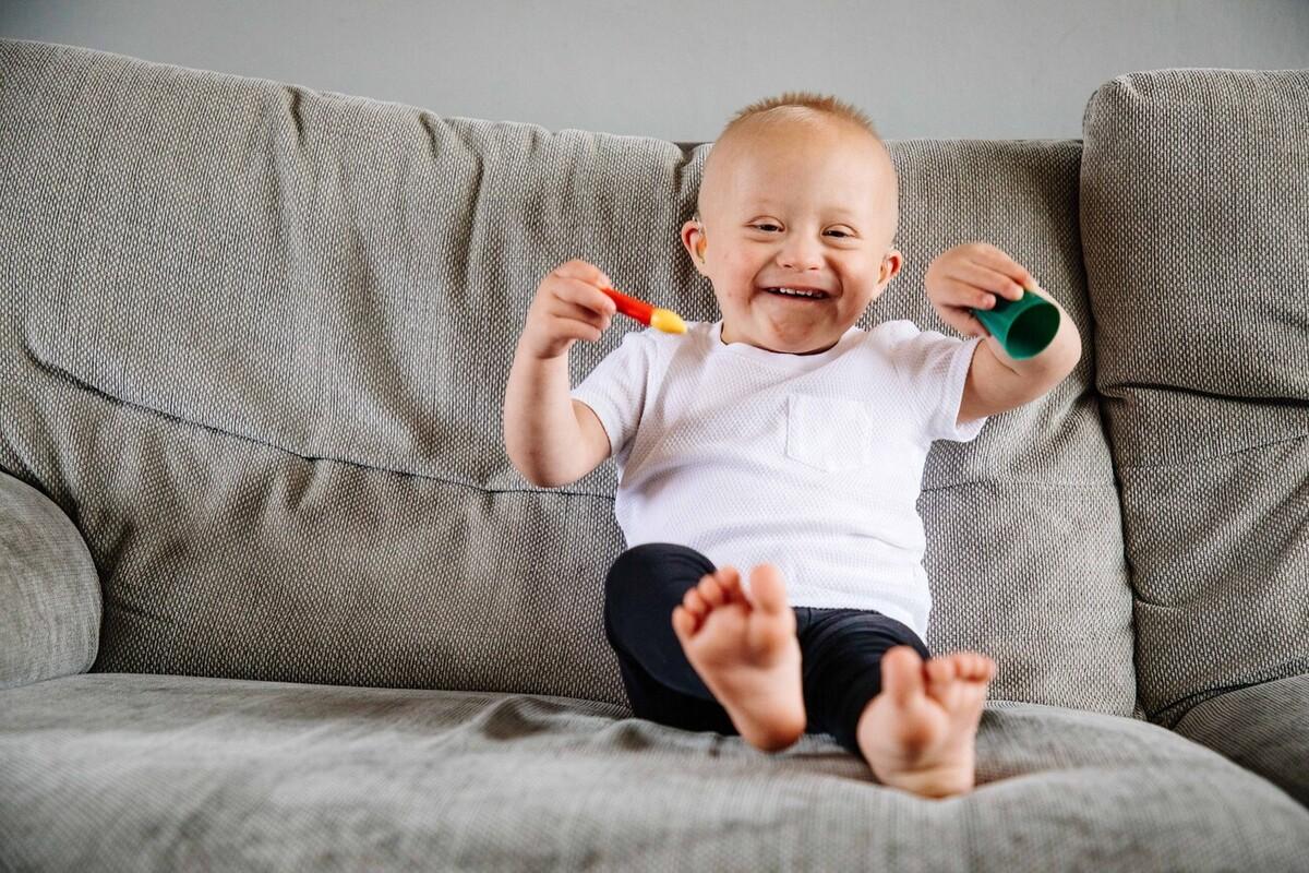 A small child with Down's syndrome plays on the sofa.