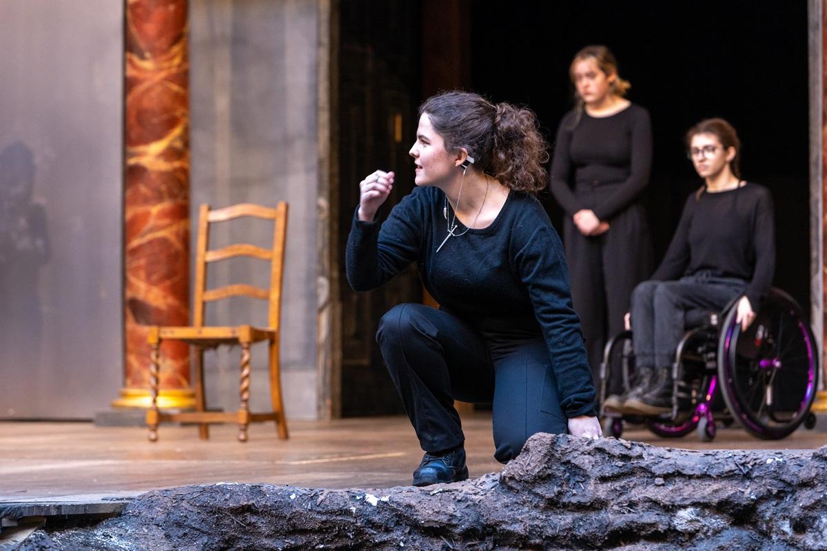 Ella wearing black, kneeling on on the stage at The Globe. Image credit: Pete Le May.