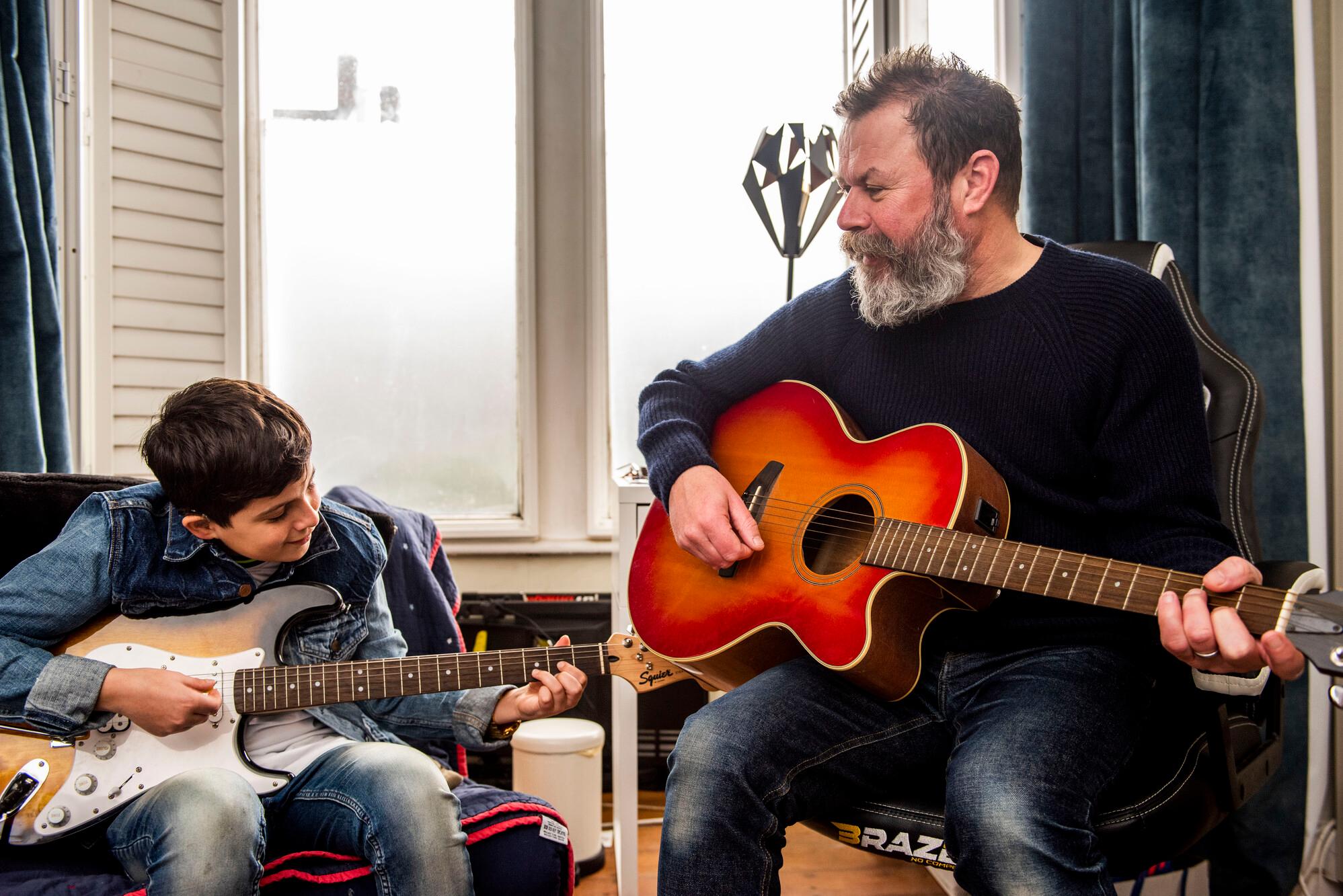 Young boy, left, plays guitar with bearded man, right