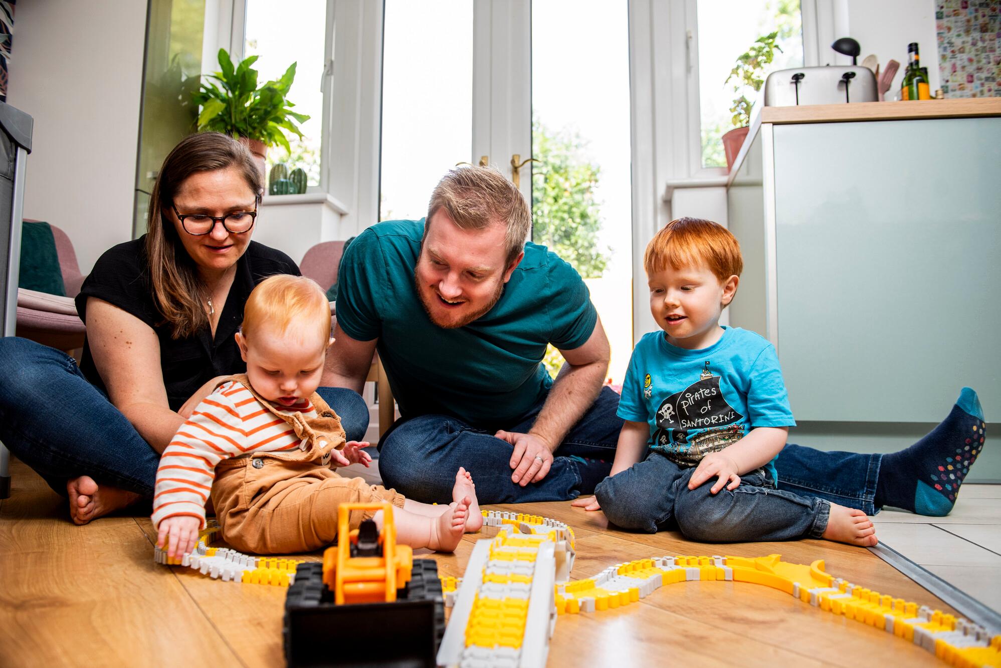 Two parents and their two young children playing with toys on the floor