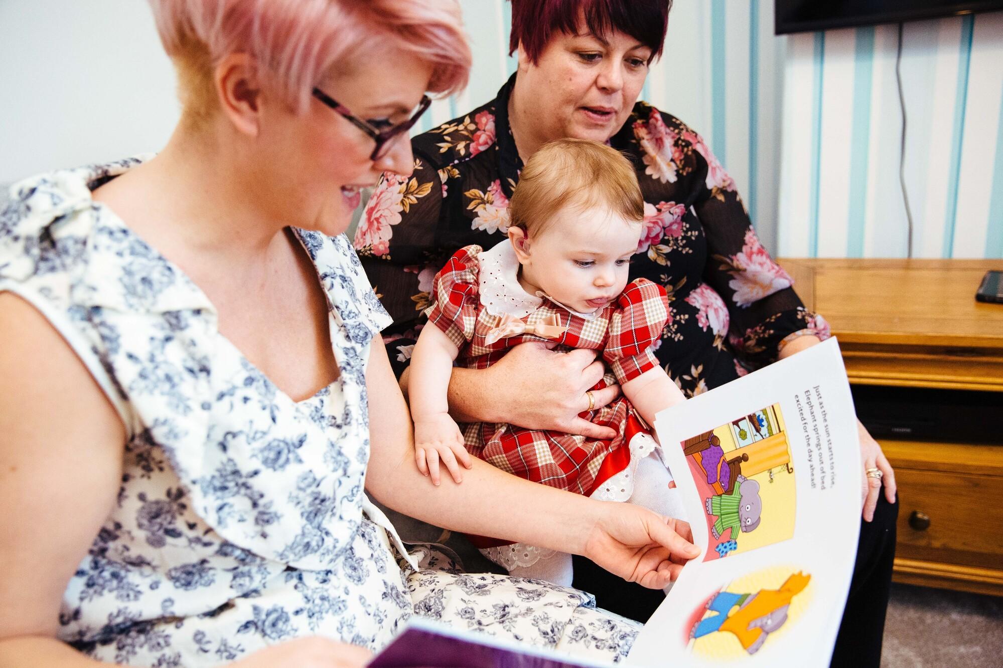 Two adults reading with a toddler 