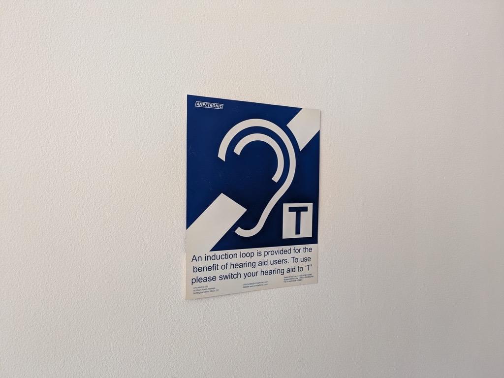 Telecoil symbol of an ear with a diagonal line through it on a blue background