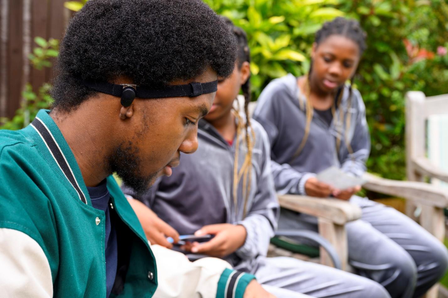 Young man wearing a bone conduction hearing aid with a soft headstrap