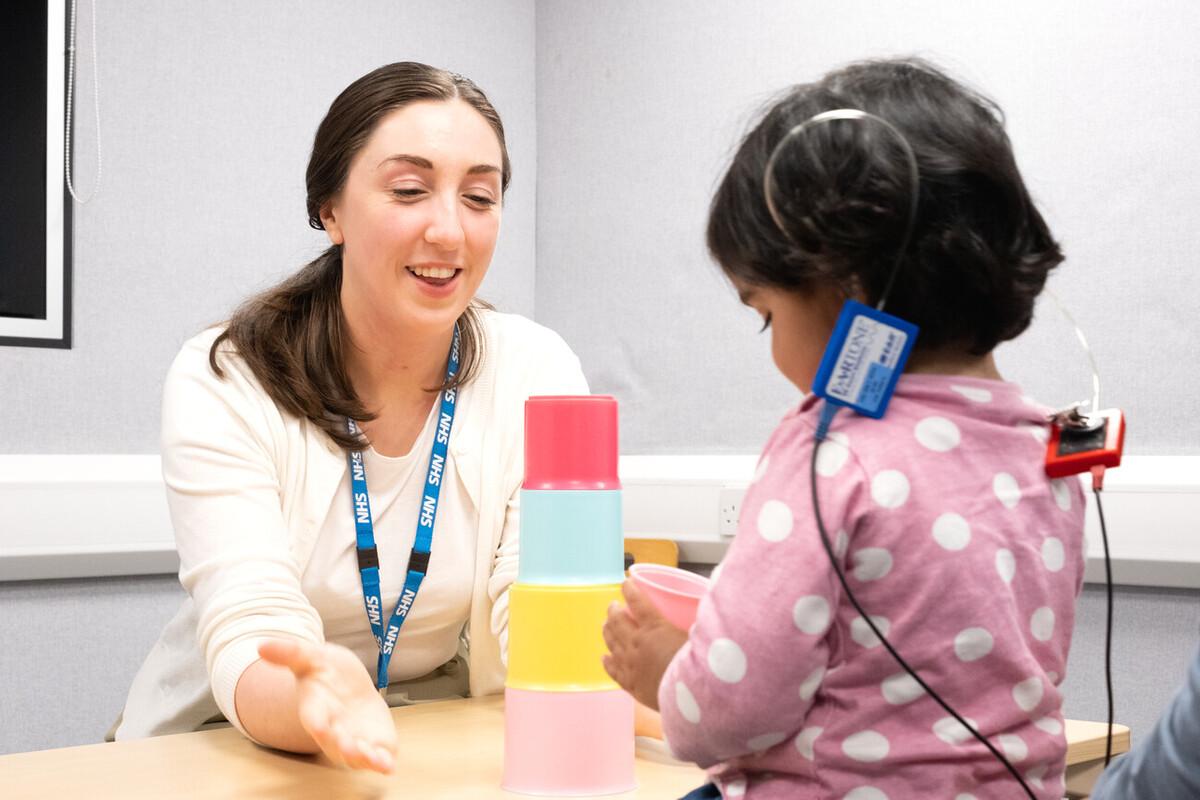 Audiologist performing a play test with a young girl during an appointment