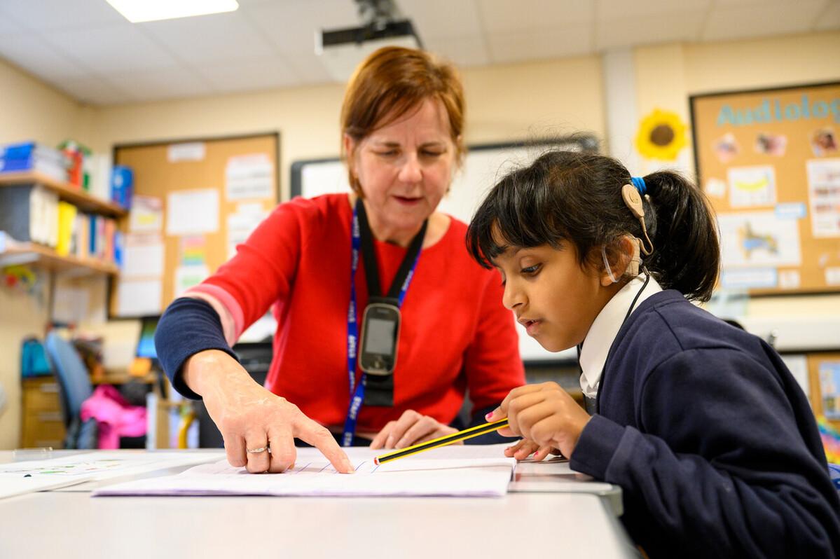 Teacher showing a young student something on a page