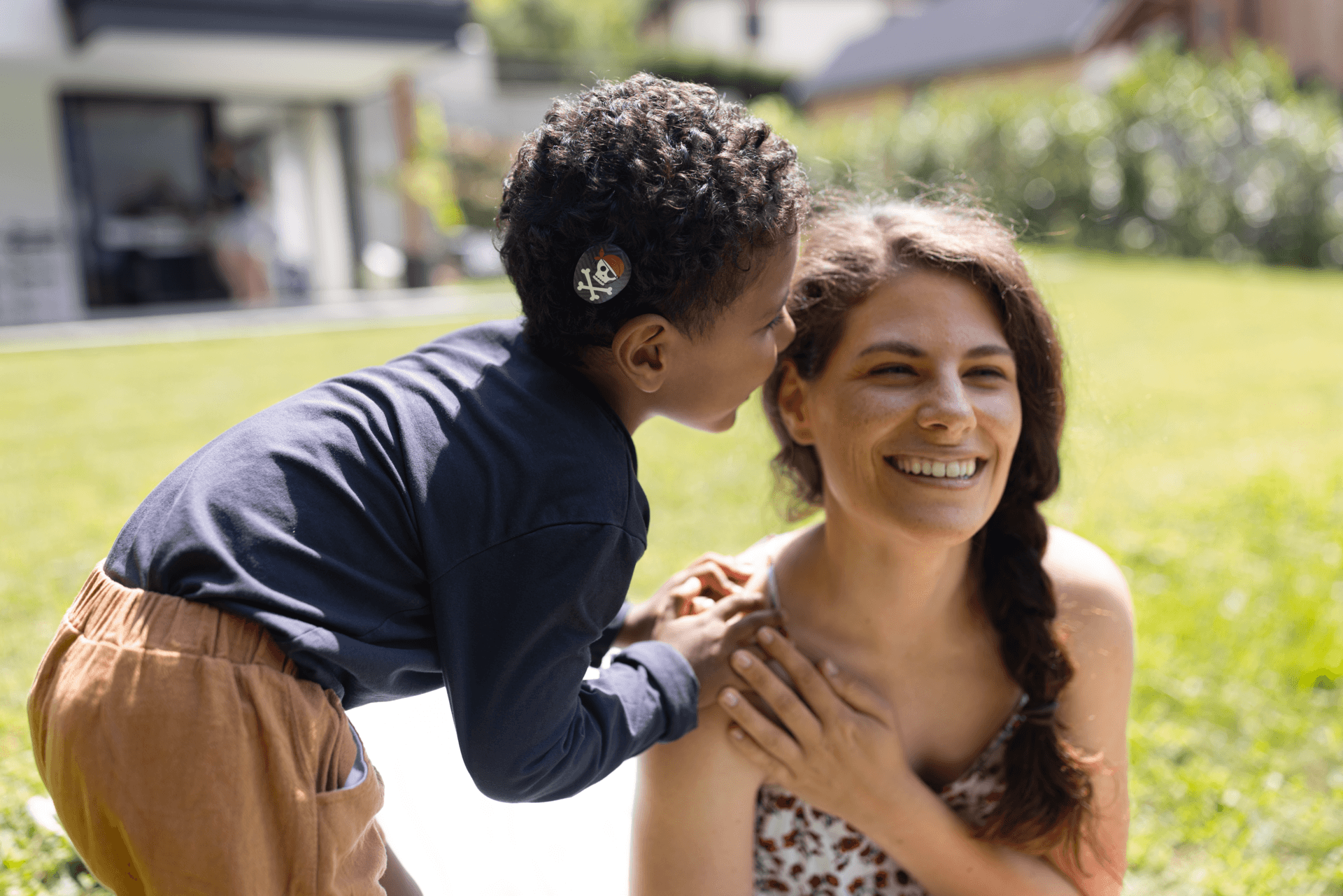 Young boy with middle ear whispering to an adult. Image copyright MED-EL