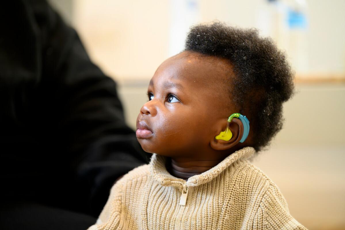 Baby with colourful hearing aid in yellow, green and blue