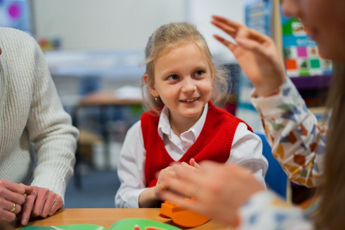 A young girl watches an adult who is talking out of shot