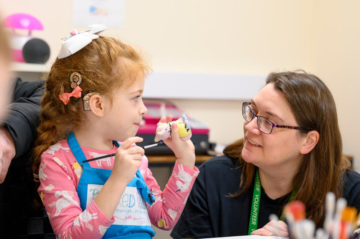 Volunteer working with a deaf child on a paint activity