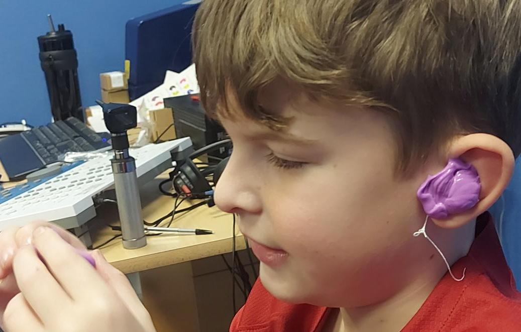 A side on photo of Oliver having new hearing aid earmoulds made.
