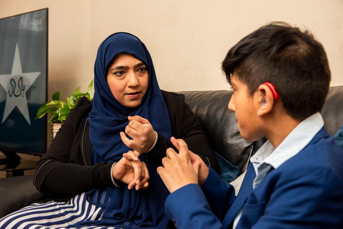 A woman and a boy in school uniform sign to each other