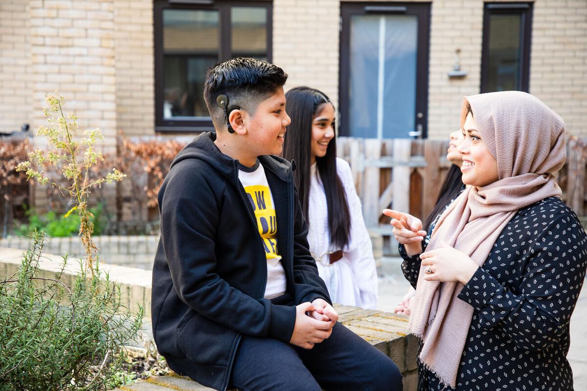 A teenage boy with a cochlear implant talks signing with his mother