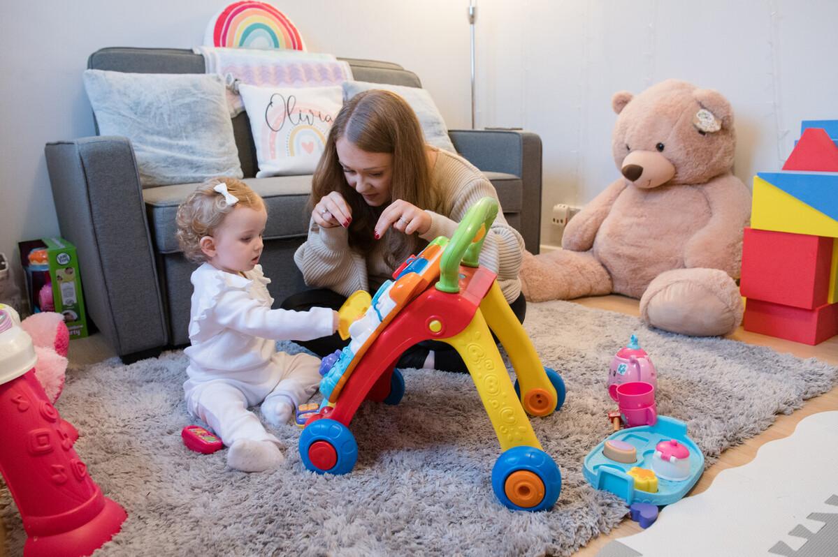 A mum signs 'dog' to her daughter while they play with a toy.