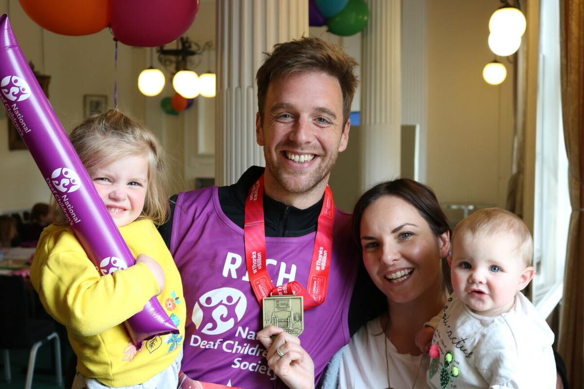 Dad who's just run a marathon standing with his wife and 2 children