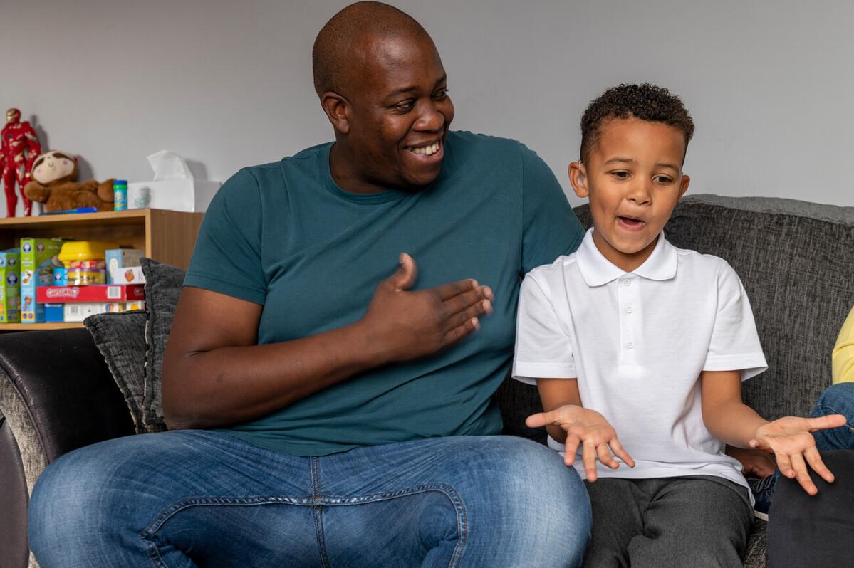 A child sits on the sofa with his dad.