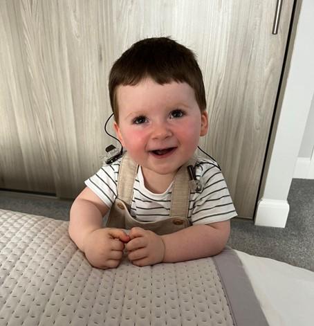 George smiling at the camera and leaning on the edge of a bed.
