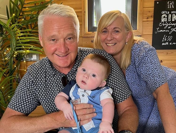 George's grandparents holding him on a table.