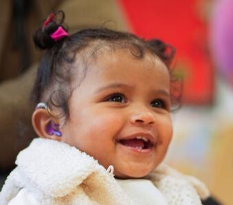 Smiling young child wearing a white top 