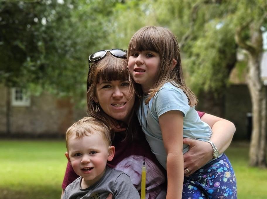 Nicky cuddling her son (left) and daughter (right) outside.