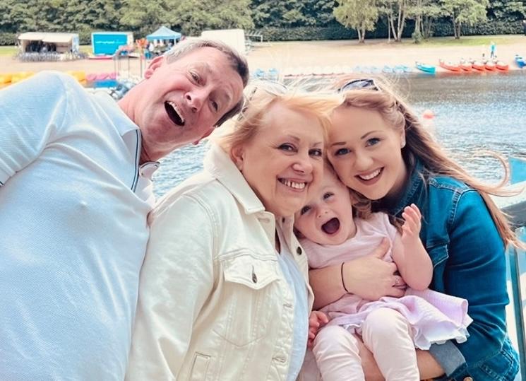 Mum, Yasmin, holding a smiling Olivia and standing to the right of Olivia's grandparents.