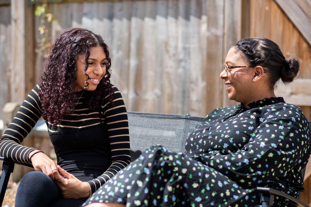 Teenage daughter and mum talking to each other on an outdoor bench