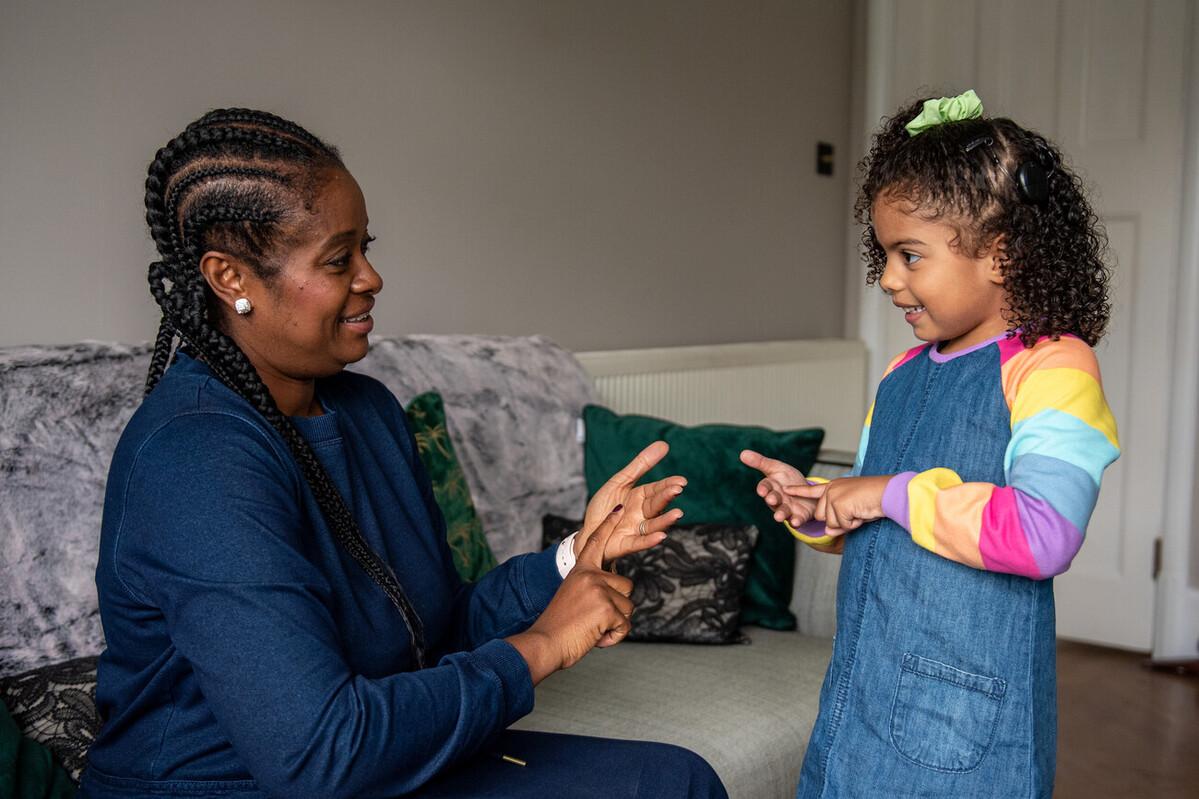 A mum signs to her daughter, who wears a cochlear implant.