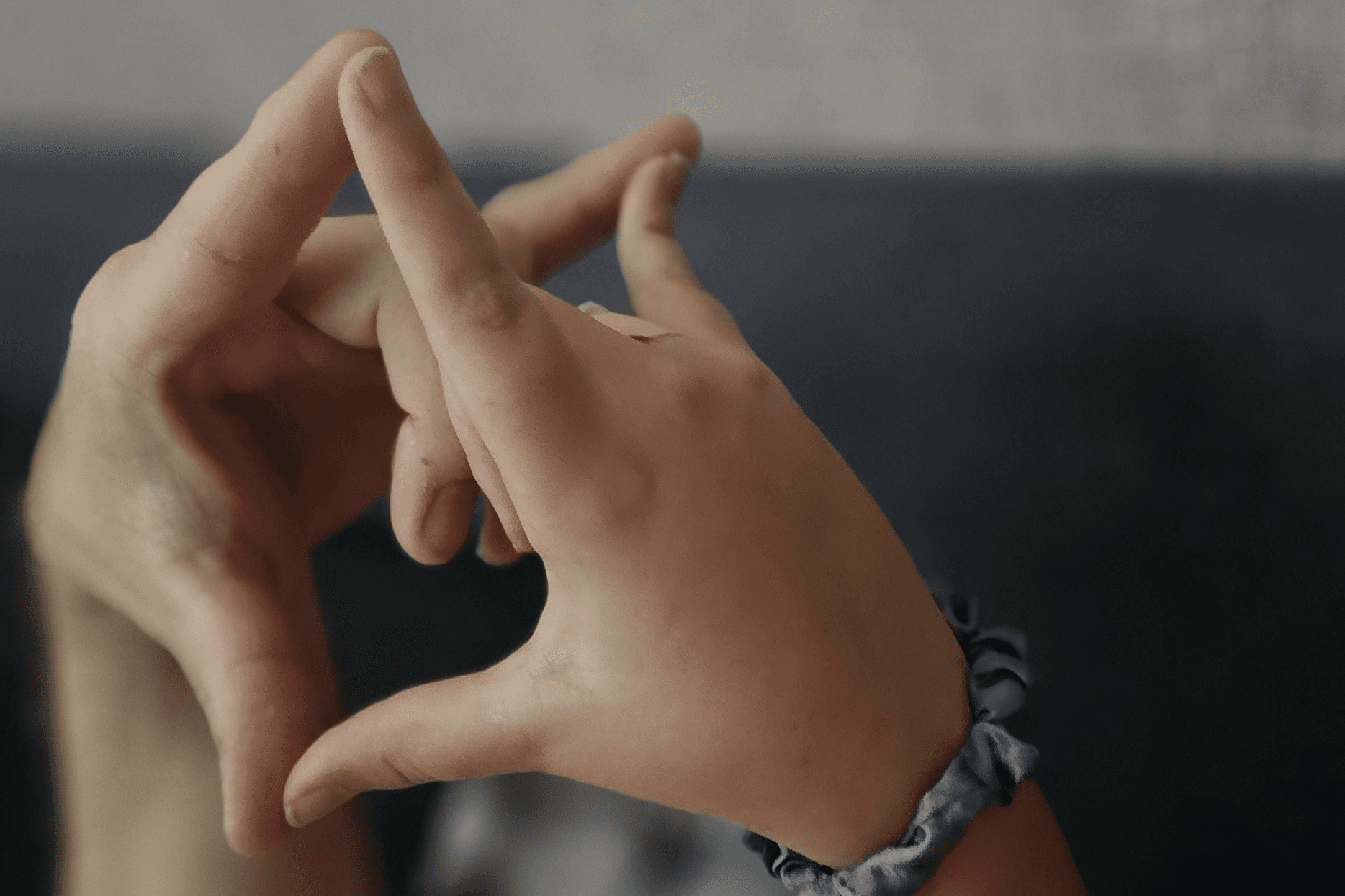 A child's and adult's hands making the ASL heart-shaped sign for 'I love you'