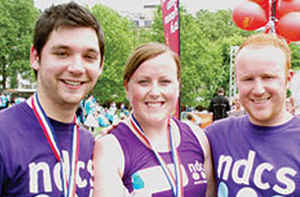 Three people smiling at the camera with their marathon medals