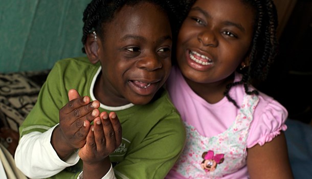 Two deaf young children smiling at the camera