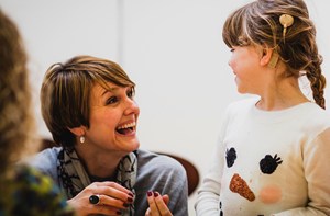 Woman crouching next to young girl wearing a cochlear implant