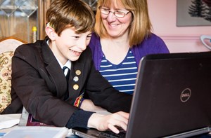 Boy at laptop with parent smiling