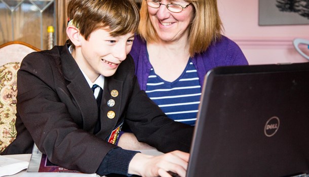 Boy at laptop with parent smiling