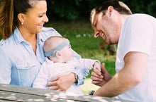 Parents and deaf baby sitting on a park bench