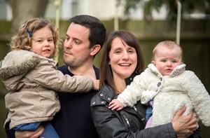 A mom and dad hold their toddler and baby. 