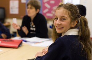 A girl with hearing aids turns around in class to smile at the camera