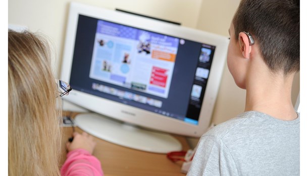 A mum and her son navigate a website together on a desktop computer.