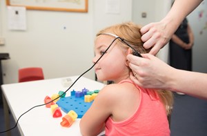 A girl with her back to the camera during audiology appointment.