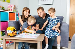 A deaf boy wearing hearing aids playing a board game with his parents and sister.