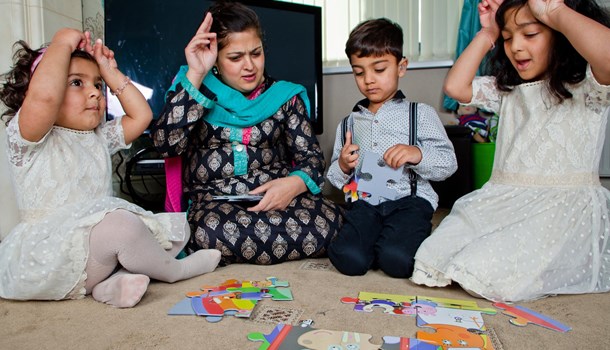 A mum and her three children play a puzzle game while signing to each other. 