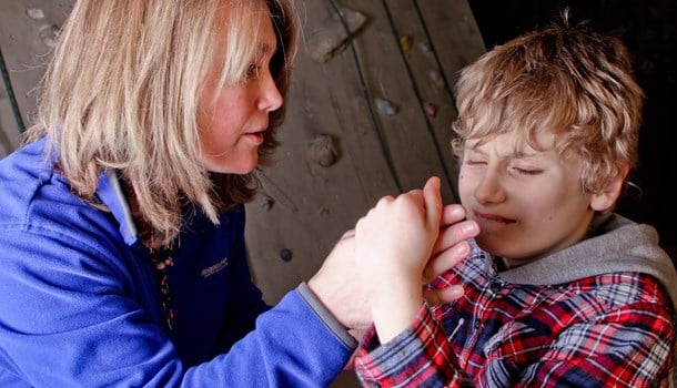 A woman uses tactile signing with a boy who is deafblind.