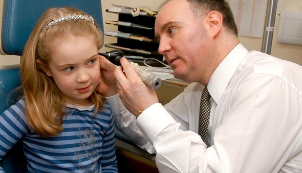 A doctor examines a girl's ear with an otoscope. 